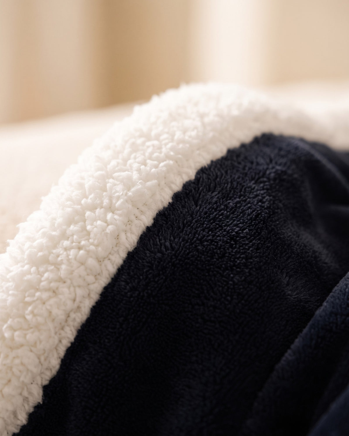 Macro of the white sherpa fleece collar and plush flannel of the Hugwarm blanket in Black